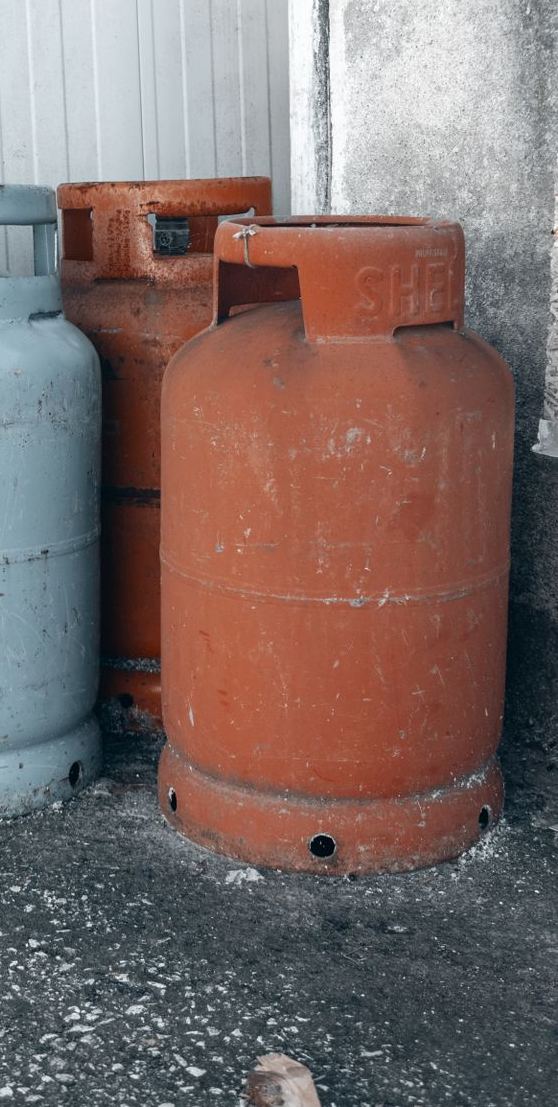 Worn LPG gas bottles stacked in a corner